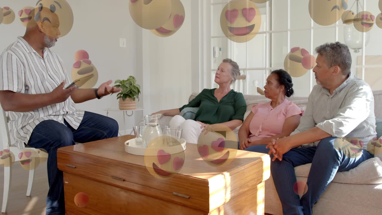 Man tapping tablet, gesturing in living room, creating emoji spheres covering group for tech demo