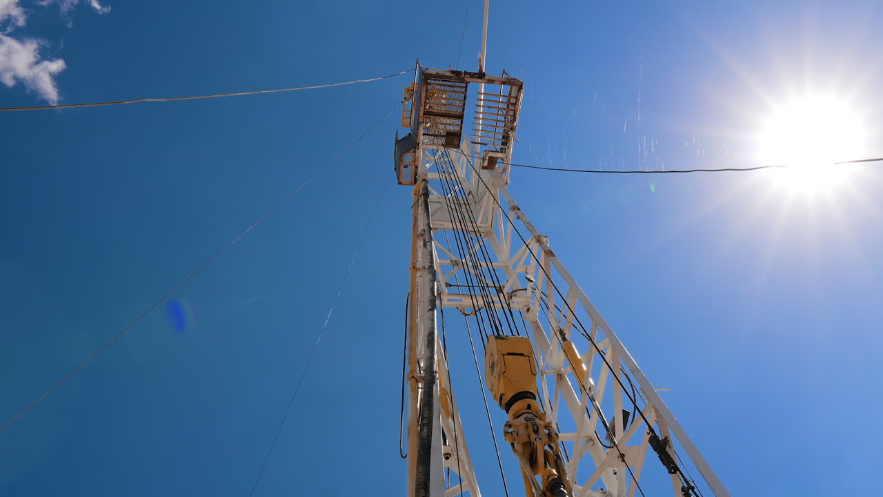 High derrick at the site for drilling natural resources. Low angle view on the rig tower for oil production.
