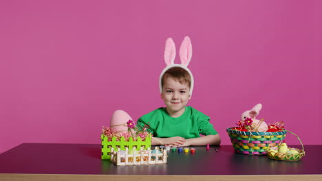 Un-Niño-Dulce-Y-Dulce-Poniéndose-Orejas-De-Conejo-Esponjosas-En-La-Cabeza-Y-Sonriendo-A-La-Cámara