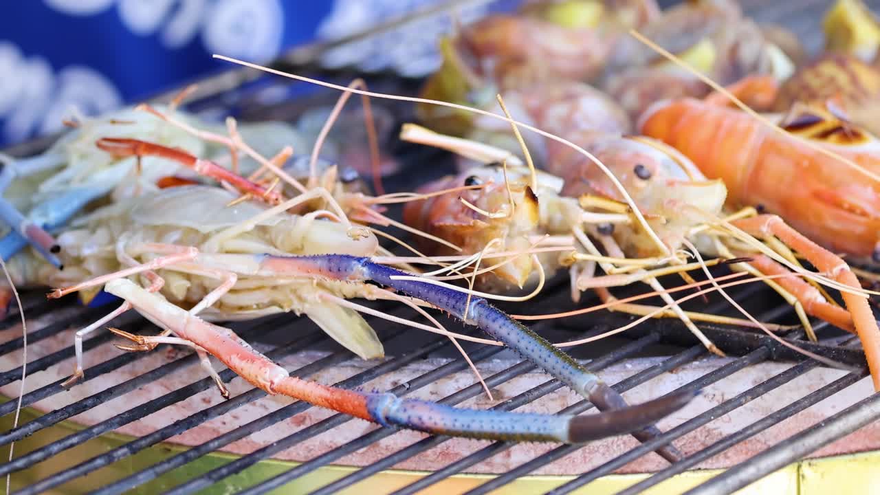 Close-up of prawns and snails sizzling on a metal grill over open flames.