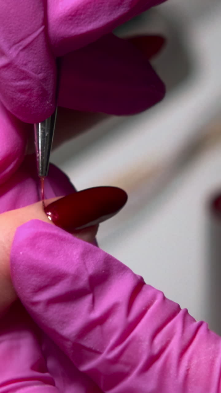 Close-up of Hands in Pink Gloves Applying Red Nail Polish