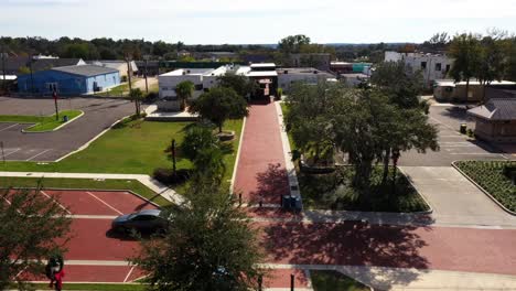 drone push in above large walkway as car zooms past on empty road, clermont florida