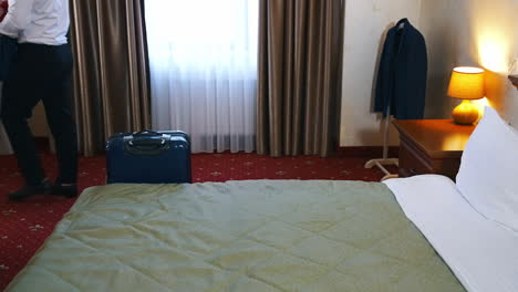 man unpacking baggage in hotel room. businessman decomposes his clothes in a luxury apartment. trip on business vacation.