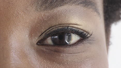 ojo de mujer negra con maquillaje mirando feliz a la cámara parpadeando belleza cosméticos fondo blanco