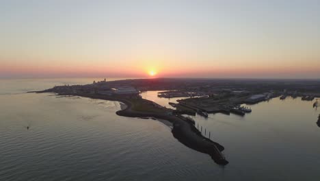 aerial: the smaller port of vlissingen, with cargo ships passing by, during sunset