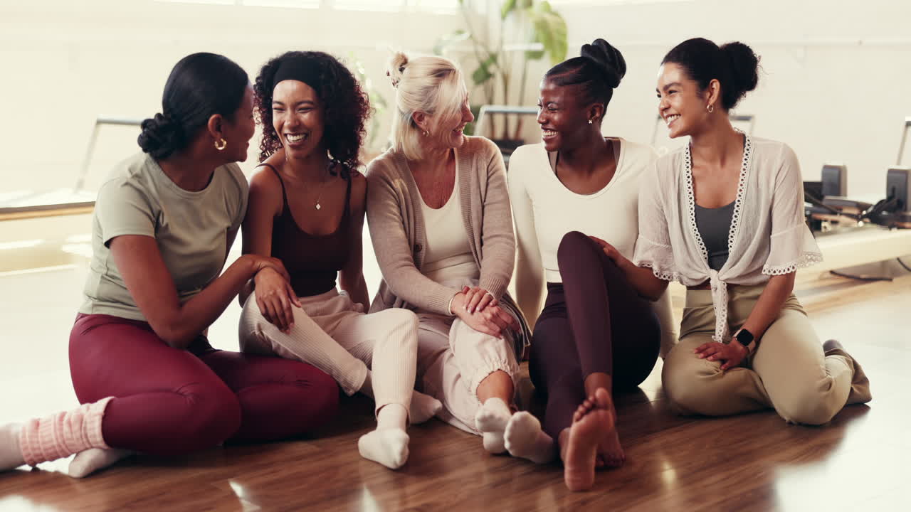 Diverse Group of Women Laughing and Sitting in Pilates Studio