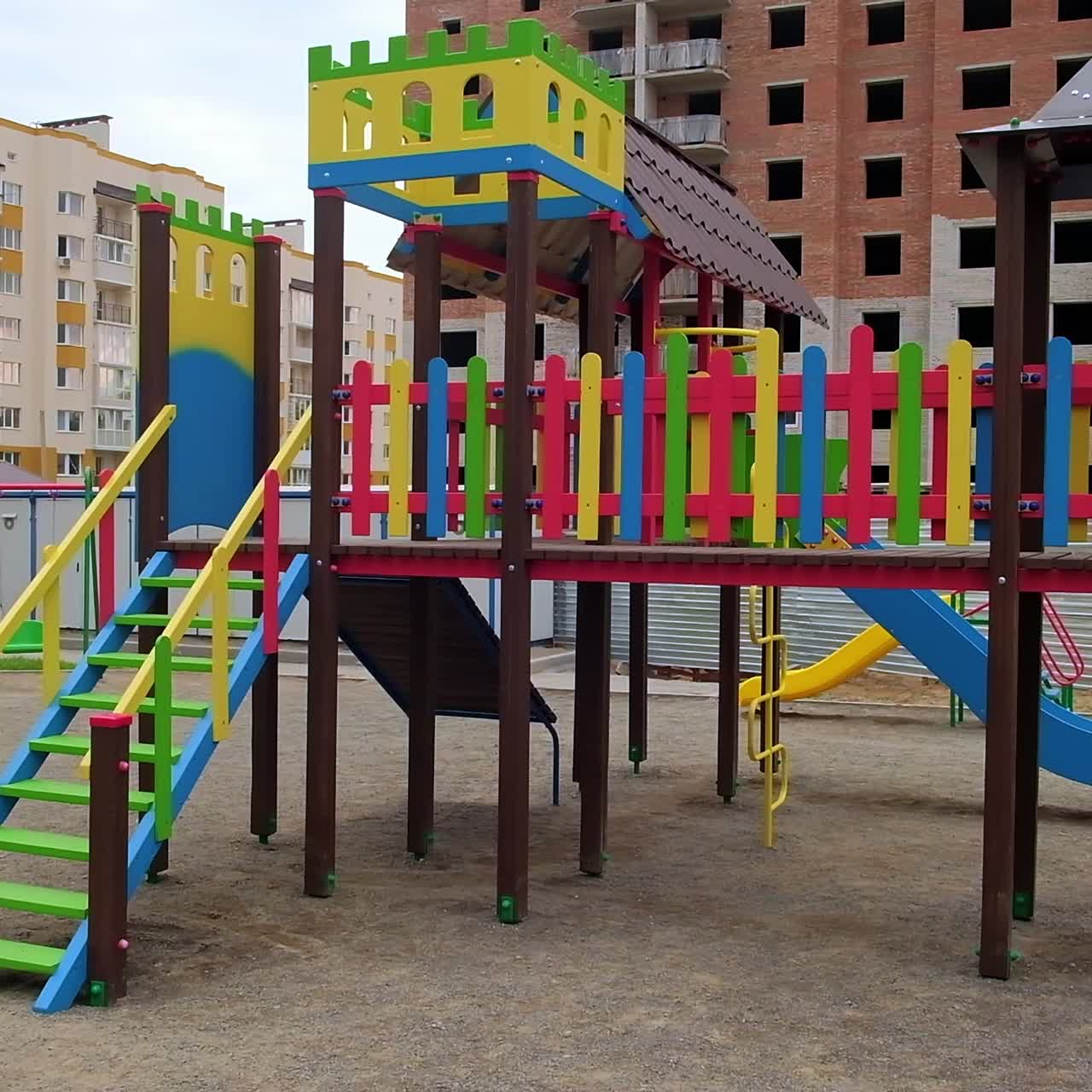 Beautiful colorful children's playground with ladders, slides and teeterboards. Multi-storied building being constructed at backdrop