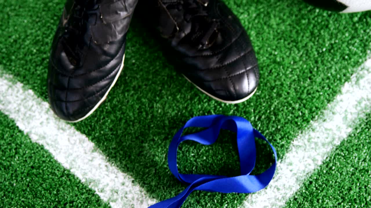 Futebol, medalha e chuteiras na grama artificial 4k
