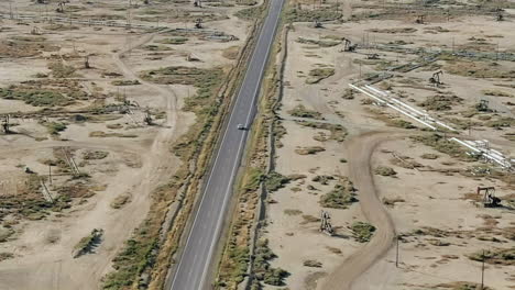 A-vehicle-driving-to-the-oil-fields-and-refinery-in-the-desolate-landscape---aerial