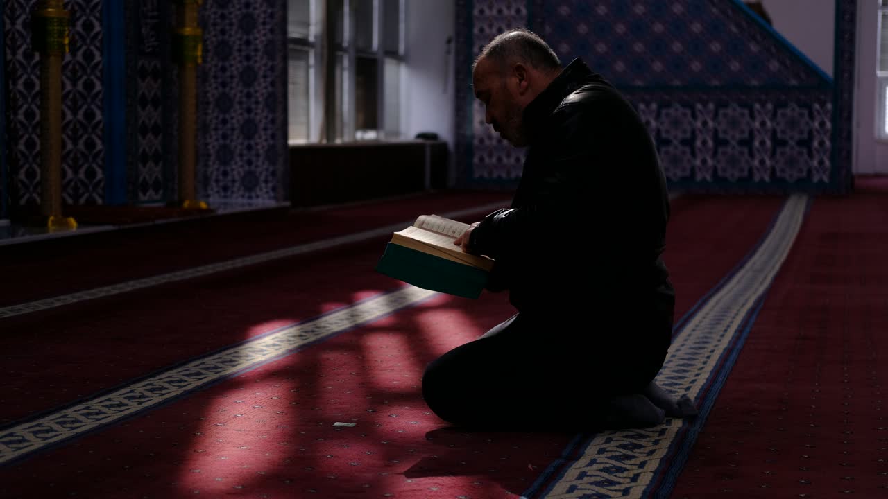 남자는 모스크 3에서 꾸란을 읽습니다.
