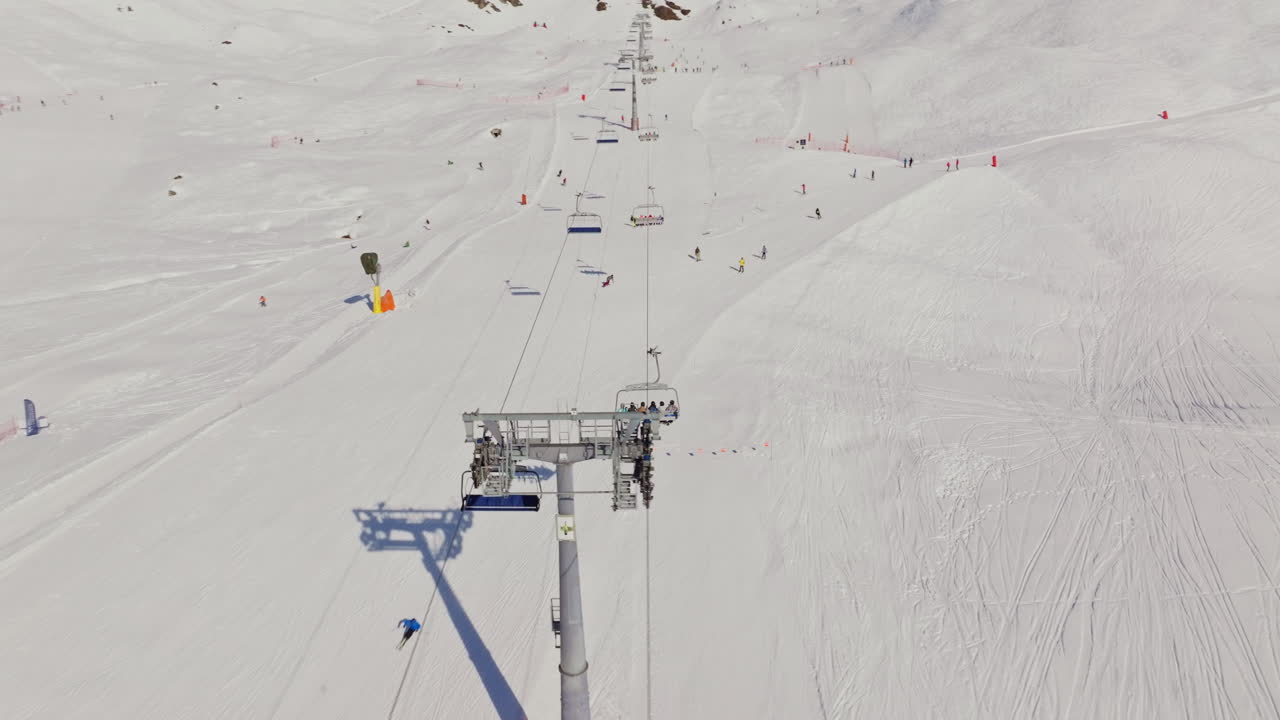 Bustling ski slopes filled with skiers and active chairlifts on a bright winter day in the Alps.