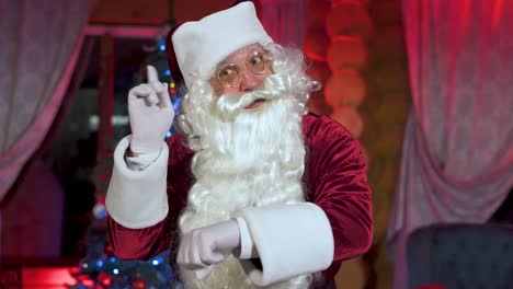 santa claus in christmas decorated room. old santa with white beard at home coming to the window at christmas night. time to carry presents to children. new year eve