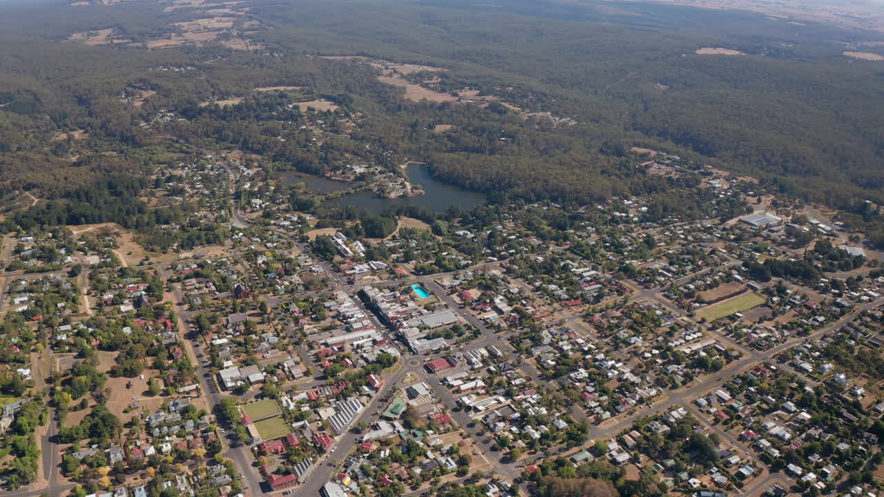 hermoso paisaje rural con lago y bosque en el fondo durante el día soleado, vuelo aéreo hacia atrás