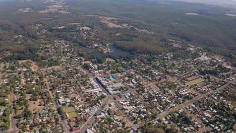 hermoso paisaje rural con lago y bosque en el fondo durante el día soleado, vuelo aéreo hacia atrás