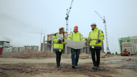 foreman architect and civil engineer are walking in building site viewing plan on paper and discussing