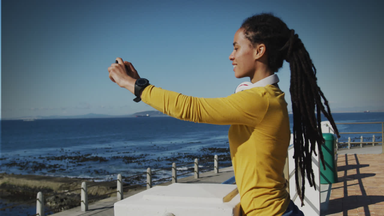 Animation of smiling biracial woman taking photo on promenade