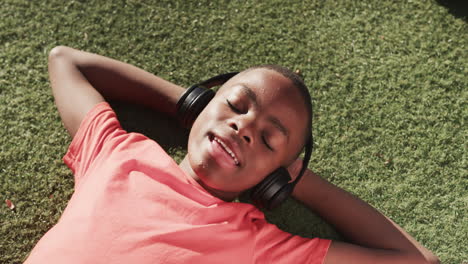 listening to music with headphones, boy relaxing on grass in schoolyard