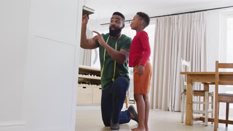 happy african american father and son measuring height, in slow motion