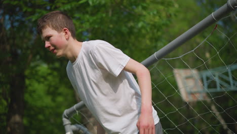 a young boy acting as the goalkeeper is standing close to the goal post, missing the ball shot at him during an outdoor football game