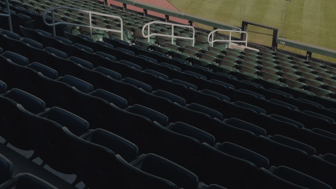 Lenta e costante panoramica da sinistra a destra attraverso le file di sedili vuoti di uno stadio di baseball.