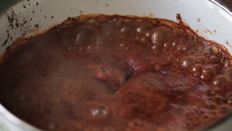 cocina casera: salsa de barbacoa roja y marrón hirviendo para la temporada de parrilla
