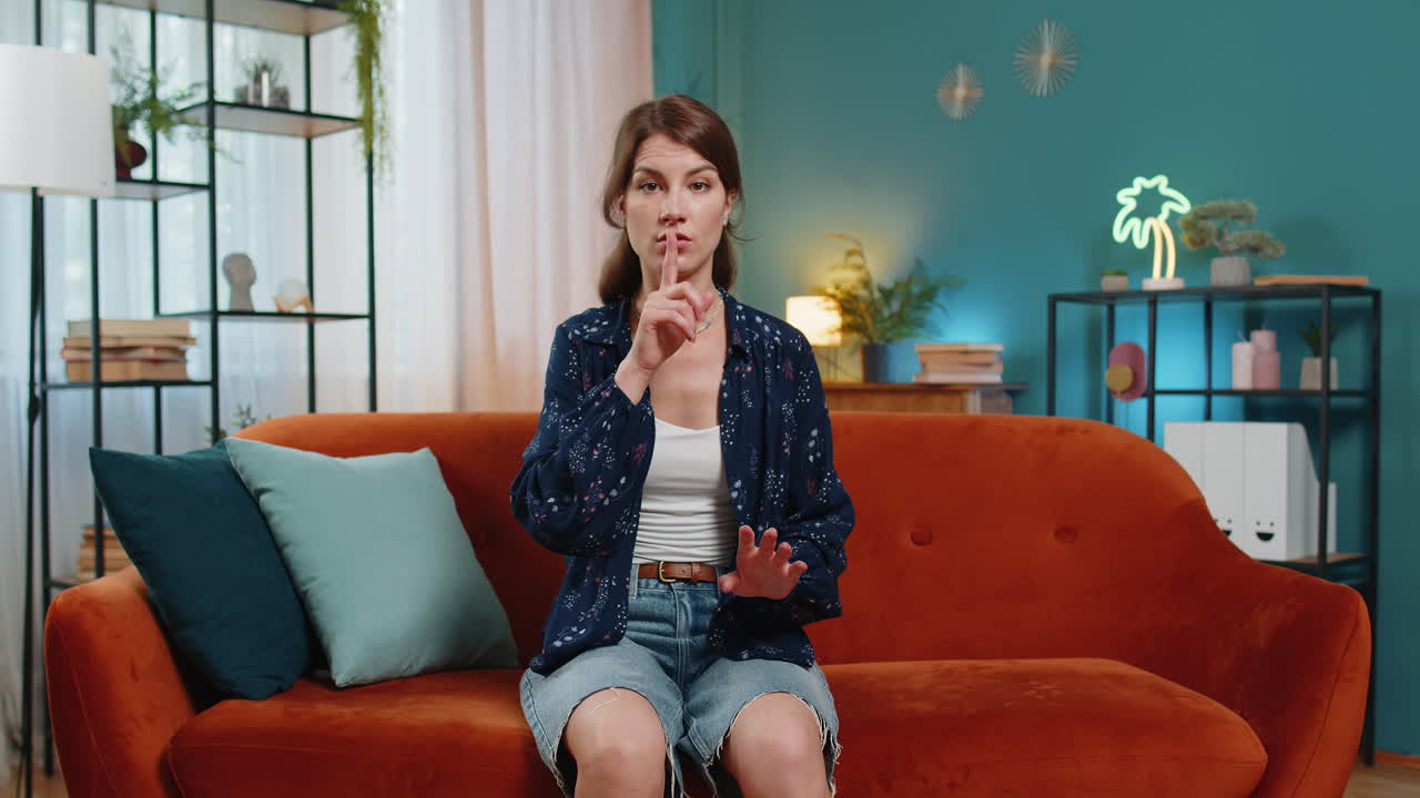 Woman presses index finger to lips makes silence quiet hush gesture sign do not tell gossip secret