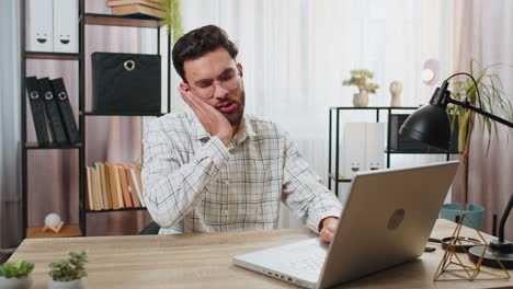 hombre de negocios indio freelance trabajando en una computadora portátil sintiendo dolor en los dientes enfermedad dental caries