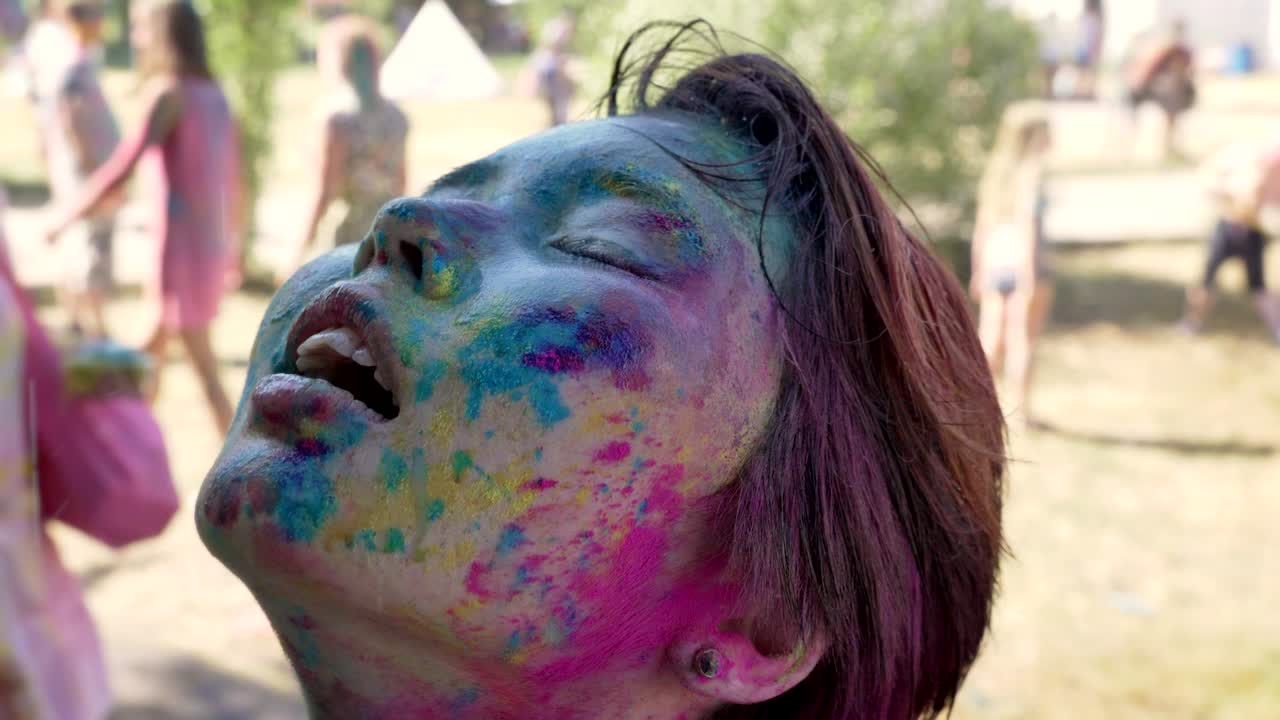 Young happy asian girl is frashing up under rain on holi festival in daytime in summer, color concept, emotional concept