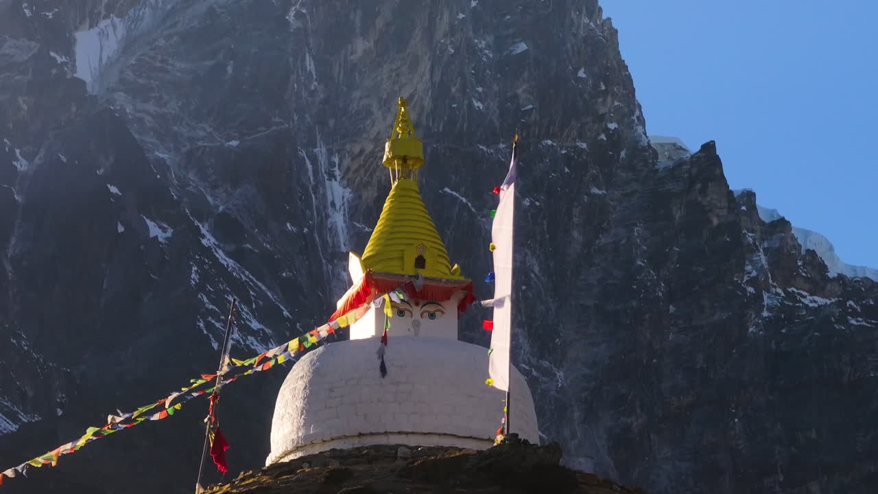 Luftoptagelse med drone, der afslører en hvid buddhistisk stupa i Dingboche, Nepal, som gradvist åbner sig mod det himalayanske bjerglandskab med bedeflag i Everest-regionen