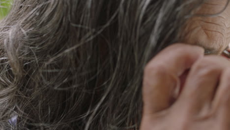 close up portrait of pretty elderly indian woman putting on glasses