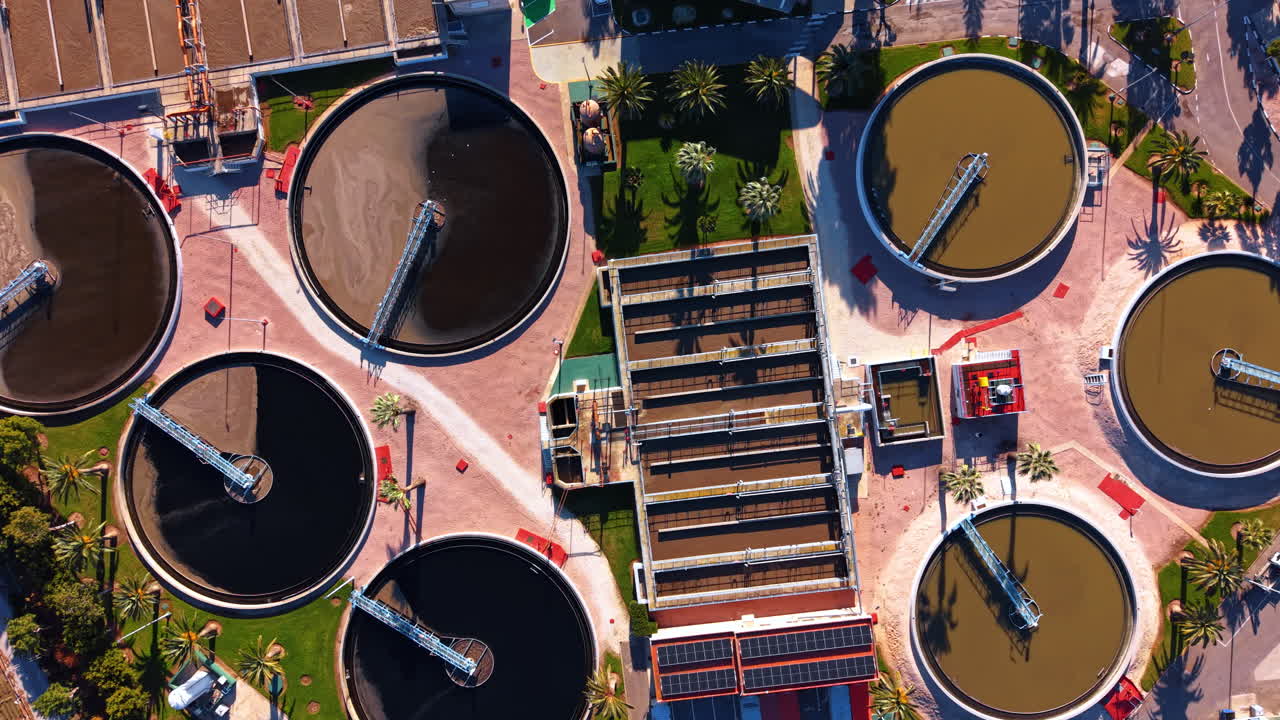 Aerial view of sedimentation tanks and aeration units. Vertical drone shot of circular water tanks and rectangular processing units at an industrial sanitation plant