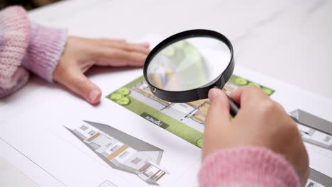 engineer using magnifying glass to examine architectural blueprints