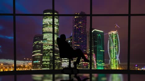 The business woman is spinning in the chair on the night city background