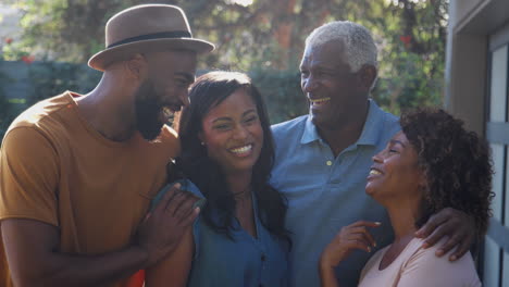 portrait of senior parents with adult son and daughter relaxing in garden at home