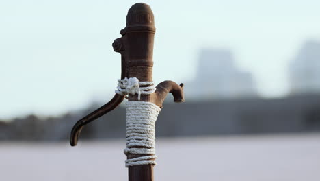 Rusty-old-metal-water-pump-on-sand-beach