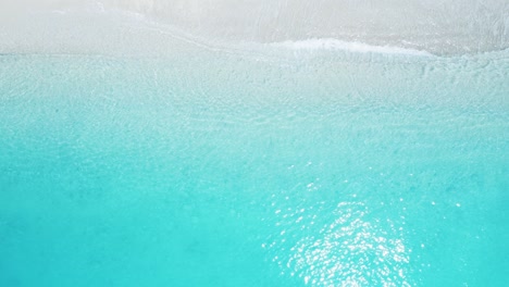 top down view of beach with blue sea and white sand.