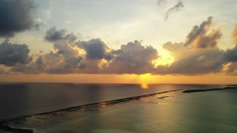 purple clouds and golden sun rays reflecting in the calm water surface