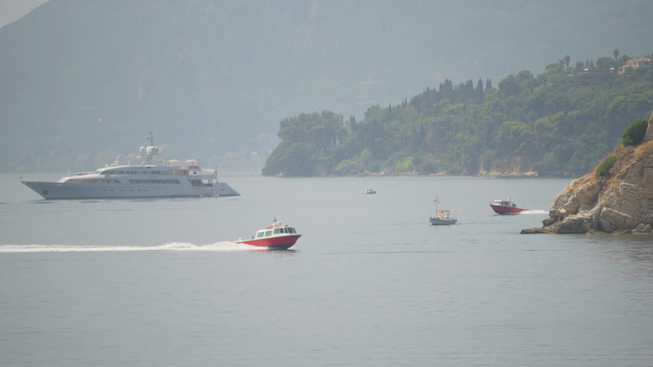 Yachts and speed boats sailing near coast of an island in Corfu, Greece. Slow motion, 4k footage.