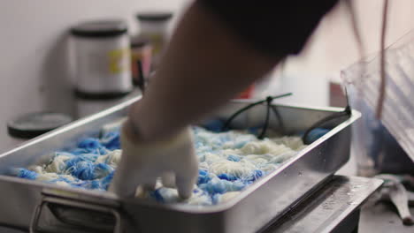 close up of a woman's hands pouring water onto dyed yarn