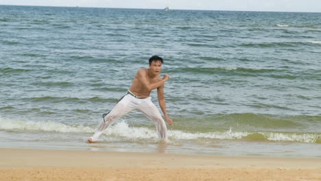 un tipo bailando capoeira en la playa.