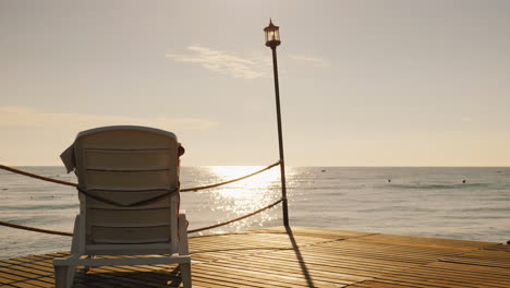 lounge for relaxation is on the pier turned to the rising sun over the sea 4k video