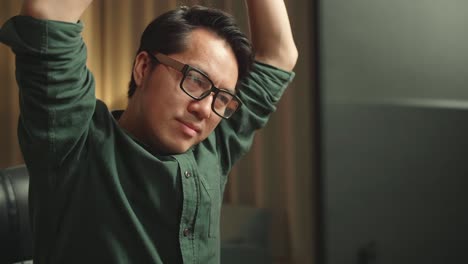 close up asian man stretching while works on personal computer and 3d printer in home office, he works at night