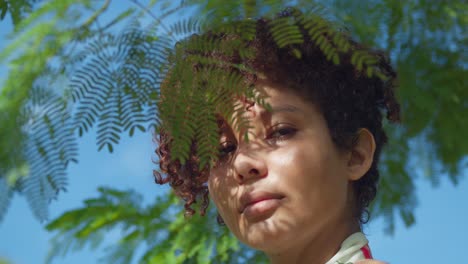 latina brown eyed girl facial close up at a park with leaves of a tree in the foreground