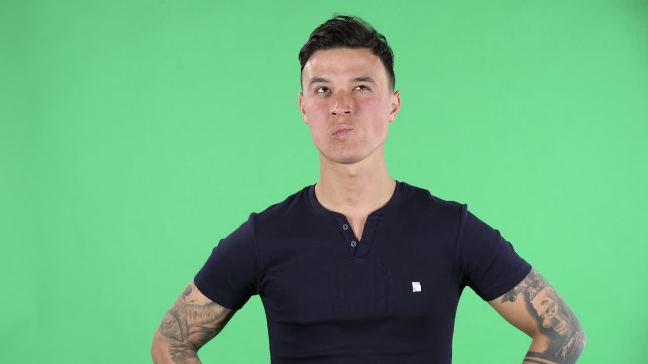 잘생긴 젊은 남자의 초상화는 쳐다보며 집중적으로 행복하게 미소 짓고 있습니다. 녹색 화면