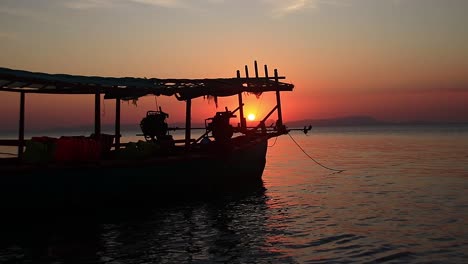 escenario cinematográfico del sol durante la puesta de sol enmarcado por la silueta de un barco de pesca frente a la costa de la isla turística de los conejos o koh tonsay en kep, camboya