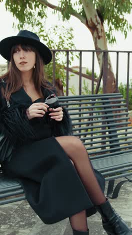 elegant woman relaxing on the park bench holding her sunglasses