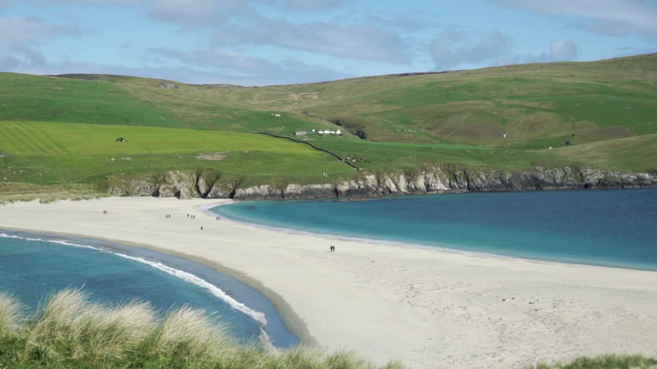 맑은 날 썰물 때 세인트 니니안 섬 모래톱을 건너는 사람들