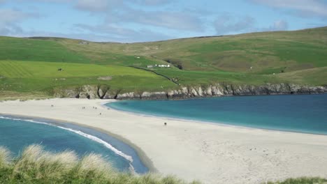 personas que cruzan la barra de arena de la isla de st ninian durante la marea baja en un día despejado