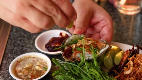 hands garnishing oysters with herbs and sauces