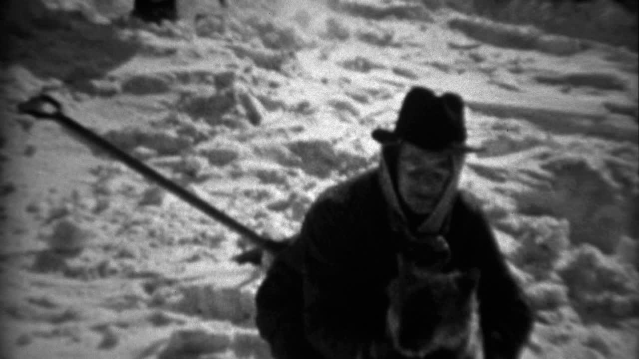 1936: hombre con sombrero fedora cuidando al perro en una escena de paisaje nevado de invierno.